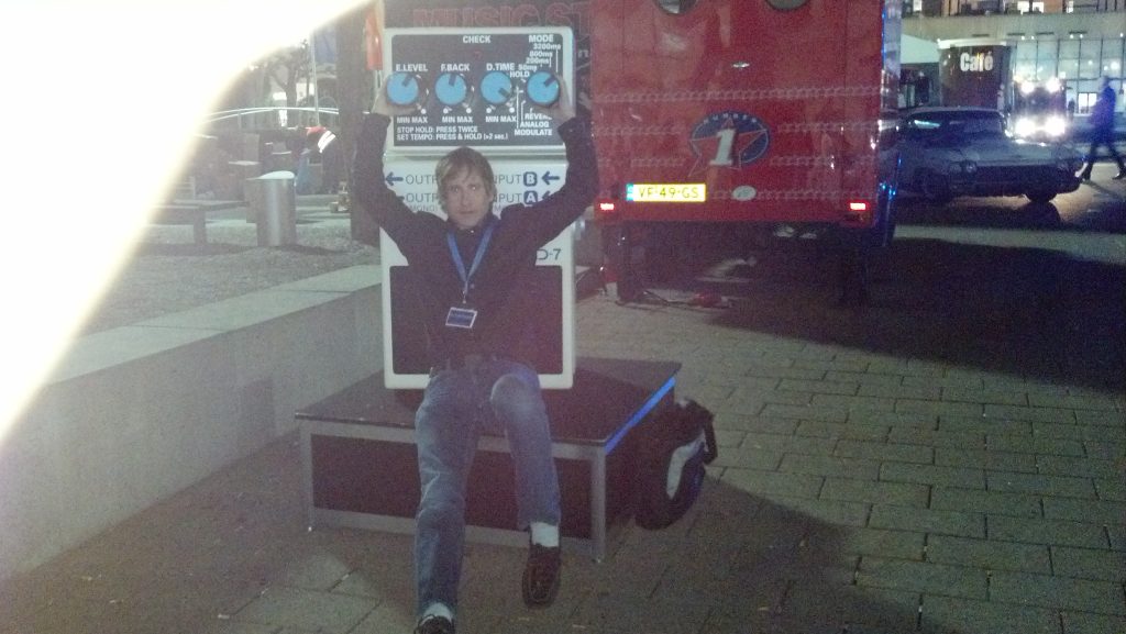 Trade show attendee holding an oversized effects pedal display at Musikmesse 2012